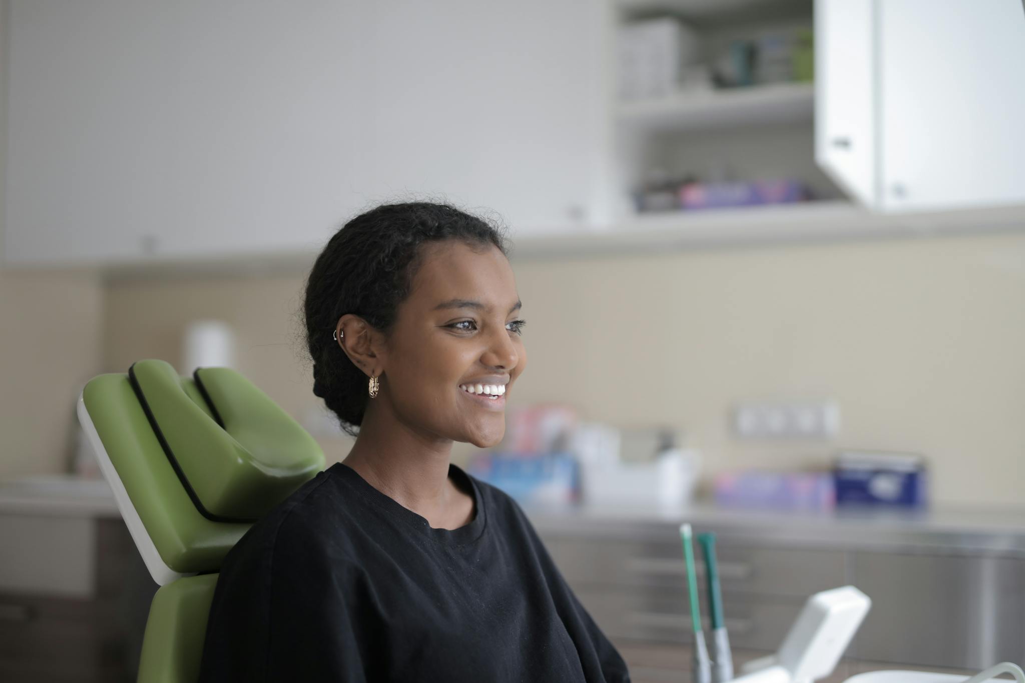 Young woman smiling in dental clinic chair, feeling relaxed and at ease.